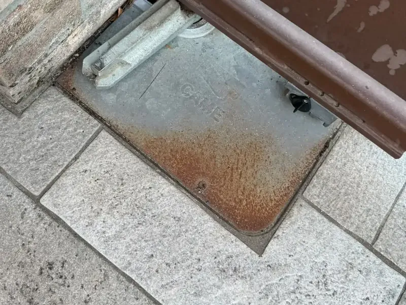 Coperchio di una cassa interrata ossidato alla base di un cancello battente
